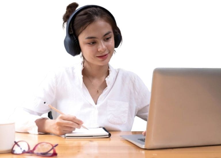 Worker Writing In Notebook and Working On Laptop